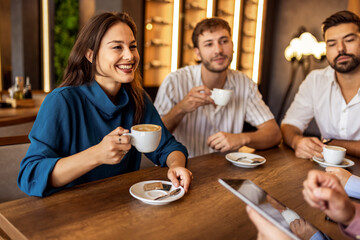 Group of young friends enjoying their time together in modern cafe, chatting and relaxing in casual social setting.