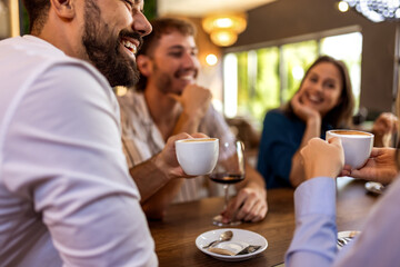 Group of young friends enjoying their time together in modern cafe, chatting and relaxing in casual social setting.
