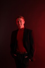 Fototapeta premium Portrait of smiling man wearing suit in neon lights against dark background