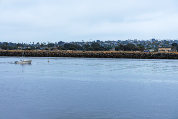 Mission Bay Entrance Channel with slowly moving motorboat near navigational buoy in a direction of the exit to Pacific ocean, San Diego, California