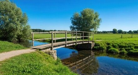 Wooden bridge spanning a tranquil river in a pastoral landscape