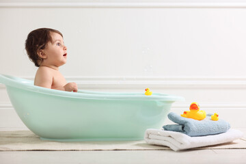 Cute little baby bathing in tub at home