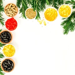 Assorted dietary supplements in small bowls, framed by pine branches