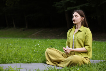 Woman meditating with crystal to heal or restore her aura outdoors, space for text