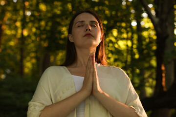 Woman meditating to heal or restore her aura in nature
