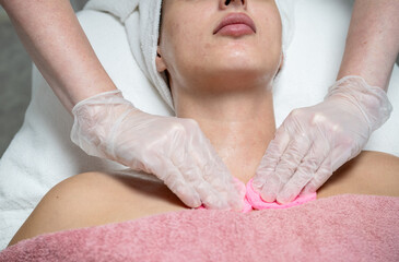 Beautician performing facial skincare treatment for female client in beauty salon