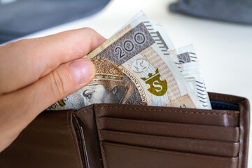 Hand pulling Polish złoty banknotes from wallet