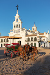 Fototapeta premium El Rocio, Sevilla, Andalusia, Spain. 28 August 2025. Horses with a cart in front of the Hermitage of El Rocio