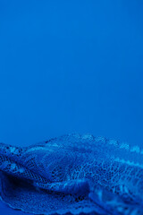 Obraz premium Blue lace fabric on blue background with copy space, vertical. High quality photo