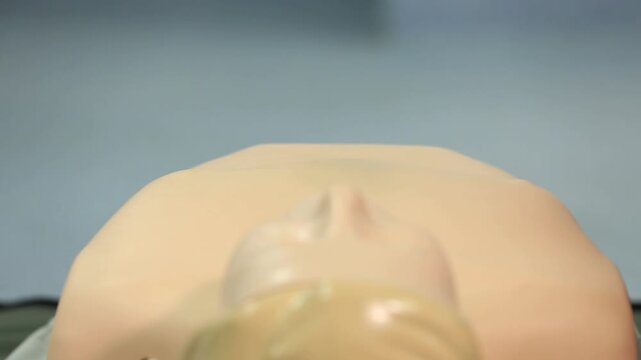 A close-up shows hands performing chest compressions on a CPR training dummy, demonstrating life-saving techniques during a first aid course.