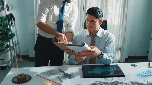 Top view of skilled businessman walking and give house design. Aerial view of architect engineer looking at blueprint and building structure at table with safety helmet and house model. Alimentation.