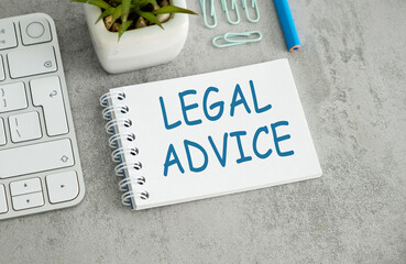 Legal Advice text on open notebook with keyboard buttons and office supplies on grey table