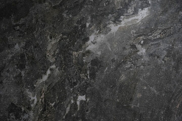 A close-up view of a dark gray stone surface with natural veins and marbled textures