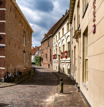 A charming cobblestone street winds through the picturesque city of Amersfoort. The architecture features traditional brick buildings with decorative shutters.