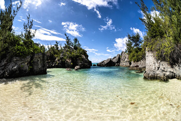 Serene Jobson's Cove, Bermuda: Crystal-Clear Turquoise Waters, Sandy Shore, and Rocky outcrops Under a Bright Blue Sky with Scattered Clouds