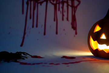 Glowing Halloween jack-o-lantern with spider and blood stains on wall symbolizing horror, darkness,...