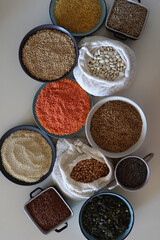 Bowls and bags full of various healthy grains and legumes. Top view.