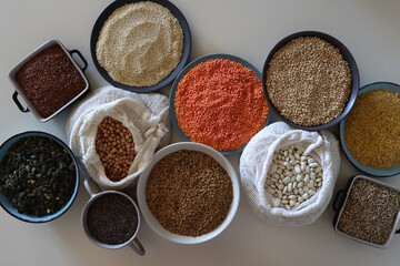 Bowls and bags full of various healthy grains and legumes. Top view.