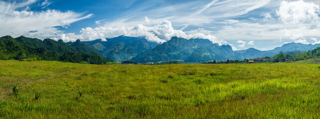 Scenic view of the grass field lawn with peaceful Mountains, Beautiful Scenery landscape with green hills in spring time. illustrating the idea of travel, tourism or exploring