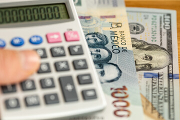 Mexico money. exchange rate of Mexican peso to dollar. Business and financial concept. 1000 Mexican pesos banknote and one hundred US dollars and a calculator