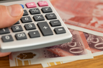 UK money. 50 British pound notes and a pocket calculator held in a hand. Financial concept, currency exchange, market rate, household budget, expense analysis