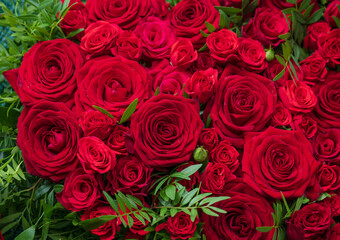 Deep red roses floral bouquet with lush green leaves.