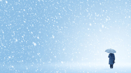 A person stands still holding an umbrella amidst a gentle snowfall in a quiet snowy landscape. Flakes swirl around, creating a magical atmosphere in the cold winter scene