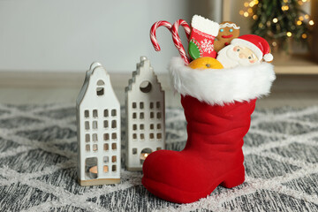 Saint Nicholas Day tradition. Red boot with treats and burning candles in room