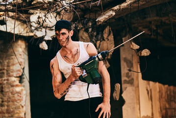 Man holding a power drill in a partially destroyed building site during broad daylight