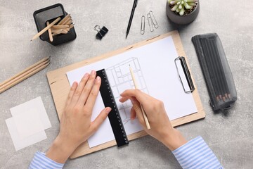 Woman drawing sketch of shelving unit at grey table, top view