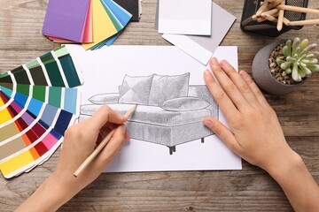 Woman drawing sketch of sofa at wooden table, top view