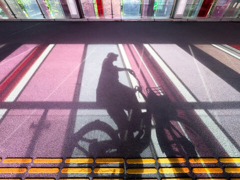 Shadow of cyclist on colorful indoor walkway floor