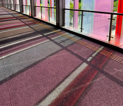 Colorful corridor with sunlight casting shadows through glass panels