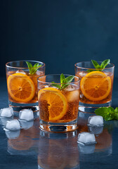 Fototapeta premium Refreshing citrus cocktails presentation with vibrant sliced oranges and fresh mint leaves against a rich blue