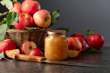 Apple jam and fresh apples on a black stone table.
