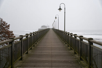 Moody wooden pier extending over water in foggy weather