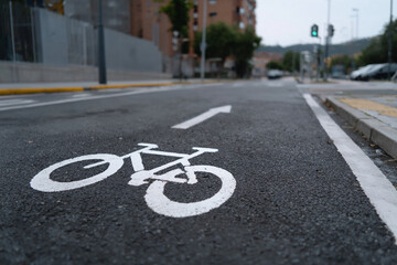 Obraz premium Pictograma de carril bici con flecha blanca pintado en asfalto de calle urbana