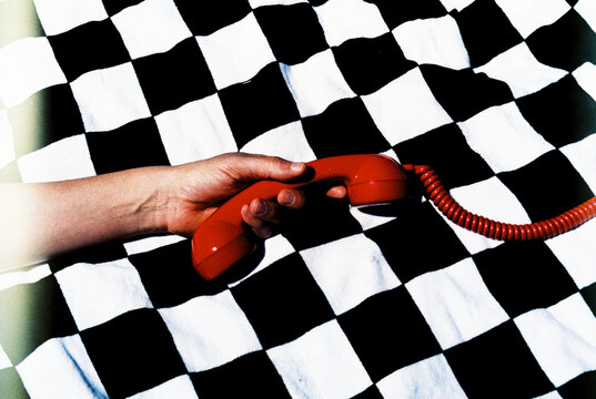 man holding a red phone on a checkered fabric, 35mm