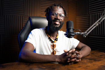 African radio host smiling during podcast recording in studio