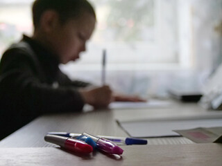 A Blurred Profile View of a Young Boy Focused on Writing in a Notebook