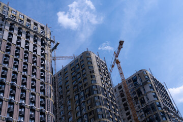 New construction towers rise against a clear blue sky with cranes in view