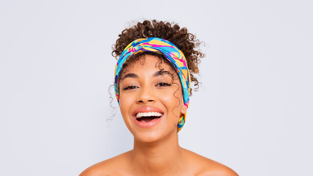 Joyful woman with colorful turban smiling in studio portrait