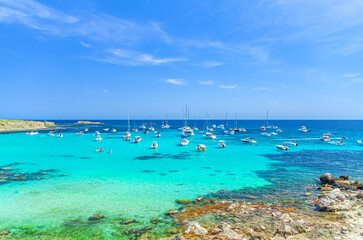 Fototapeta premium Yachts and motor boats anchored in azure turquoise water of lagoon Alicante bay Mediterranean Sea near coast Tabarca Island Nueva Tabarca Isla Plana in sunny summer day, Valencian Community, Spain