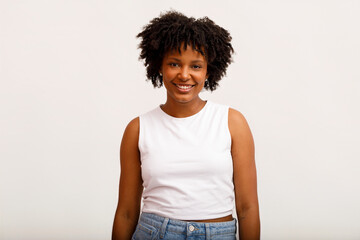 Young Woman With Curly Hair Smiling Against a Plain Background