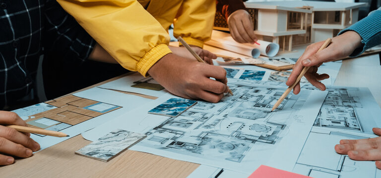 A vibrant collaborative design session showcasing diverse hands engaged in creating architectural blueprints and models, highlighting teamwork and creativity in a bright workspace. SACTR