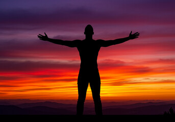 Fototapeta premium Man silhouetted against vibrant sunset, arms outstretched, embracing freedom and new beginnings