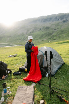 young hiker taking folding up his camp in Alps
