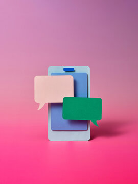 Paper smartphone displays speech bubbles representing