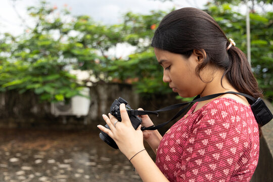 Young Indian woman previewing photographs in mirrorless camera