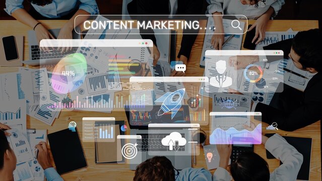 A group of professionals engaged in a collaborative meeting, analyzing digital marketing metrics and data visualizations with laptops and documents on a modern office table. Raster